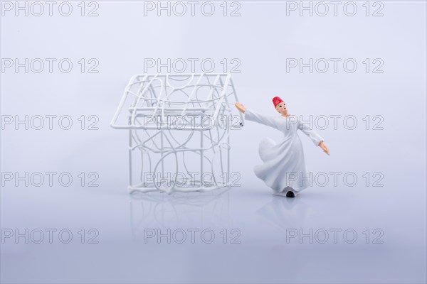 Sufi dervish and a little metal house on a white background