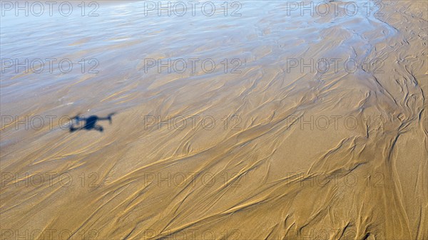 Drone shadow on sandy beach