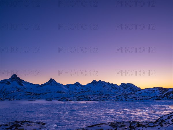 Snowy mountains above the frozen Kong Oscar Fjord at dawn