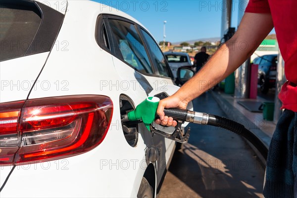 Man with the gun refueling gasoline or diesel fuel in a white car. Concept of transportation