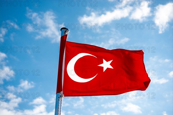 Red Turkish flag on pole on a cloudy sky