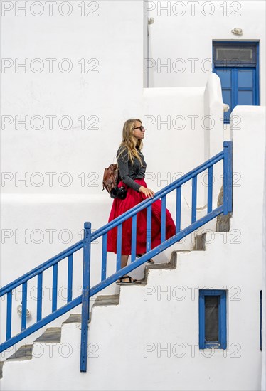 Young woman with red skirt on a staircase with blue banister