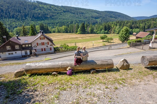 Hiking couple sitting on wooden trunk on the hiking trail Sprollenhaeuser Hut