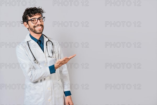 Young doctor presenting something with palms isolated. Handsome doctor showing an advertisement with his palms