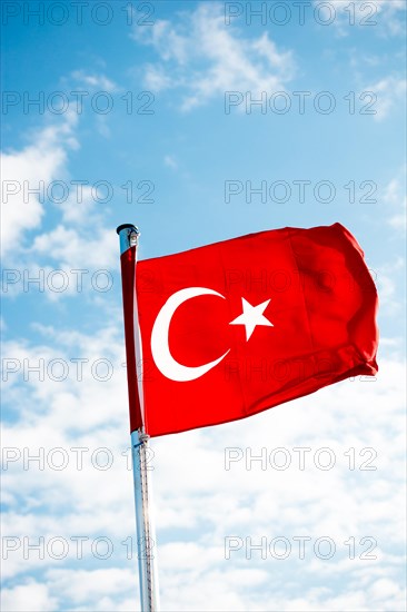 Red Turkish flag on pole on a cloudy sky