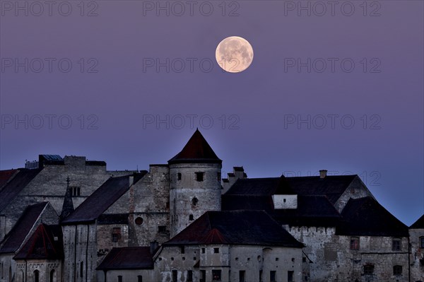 The full moon sets behind the castle in Burghausen