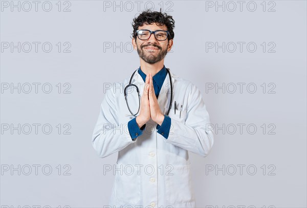 Smiling doctor putting palms together on isolated background. Handsome doctor with hands together isolated. Young doctor with palms together