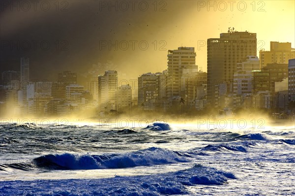 Summer sunset at Ipanema beach in Rio de Janeiro with the light crossing the buildings until arriving at the sea