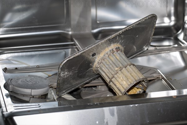 A heavily soiled drain strainer in a dishwasher