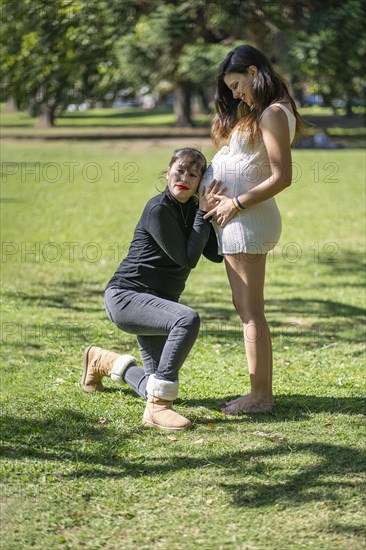 Woman listening to his pregnant girlfriend's tummy