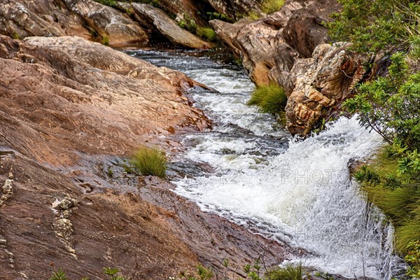 Small river and cascade between the rocks and the arid vegetation of the Biribiri environmental reserve in Diamantina