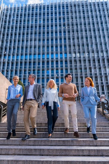 Cheerful group of coworkers outdoors in a corporate office area going down some stairs going to work