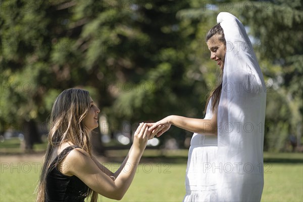 Couple of women getting married outdoors. Pregnant woman getting married. Woman putting ring on her partner