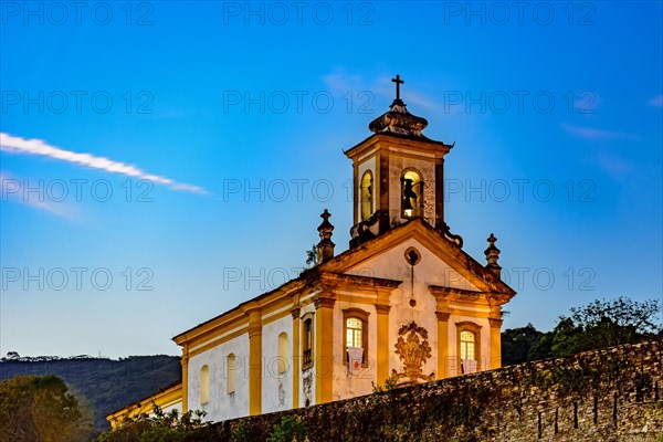 Old and historic 18th century church with its facade illuminated at dusk in the city of Ouro Preto