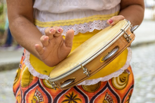 Young woman in colorful clothes playing the tambourine during a samba performance in Salvador