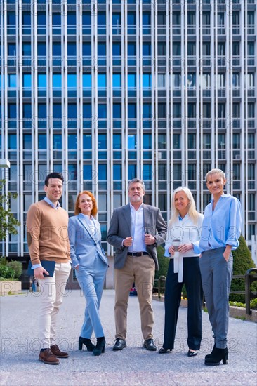 Portrait of cheerful group of coworkers walking outdoors in a corporate office area laughing