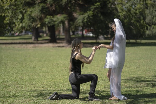 Couple of women getting married outdoors. Pregnant woman getting married. Woman putting ring on her partner