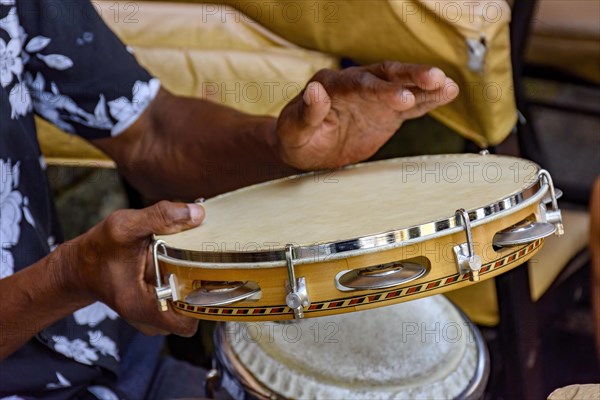 Hands and instrument of musician playing tambourine in the streets of Salvador in Bahia during a samba performance during carnival