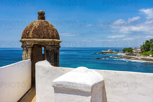 Wall and guardhouse of an old historic fort on the edge of the city of Salvador in Bahia with the sea and the city in the background