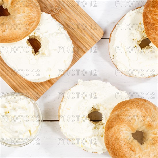 Bagel sandwich for breakfast topped with cream cheese on wooden board from above square in Stuttgart