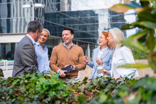 Chatting next to a green area. Group executives or businessmen and businesswoman in a business area