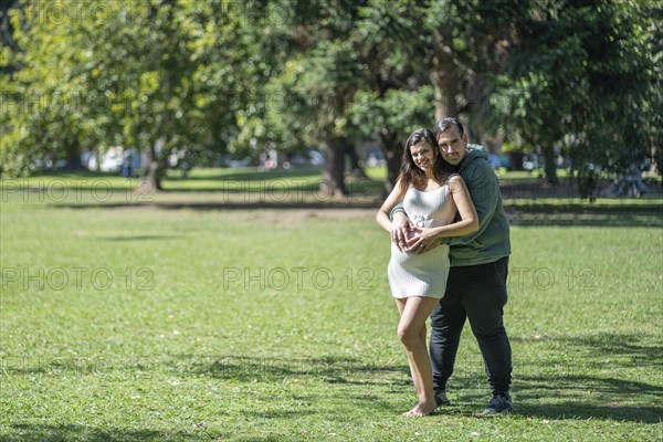 Pregnant woman posing with her partner outdoors