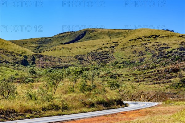 Empty road between the hills with stones and vegetation
