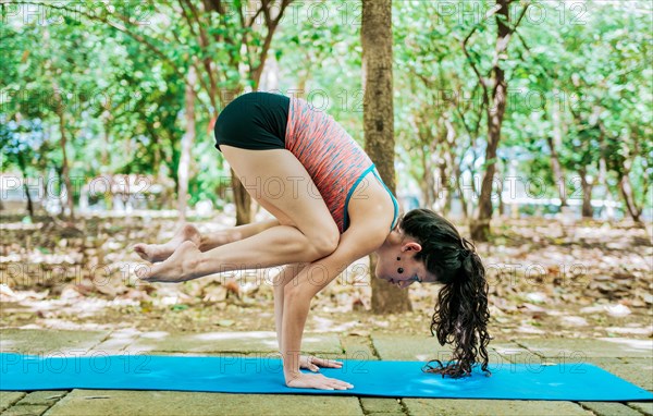 Young woman doing yoga crow pose outdoors. Girl doing yoga bakasana or crow pose in nature