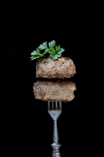 Two homemade meatballs on fork