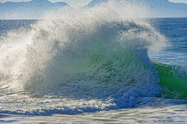 Wave breaking on the beach at dawn with mountains in the background