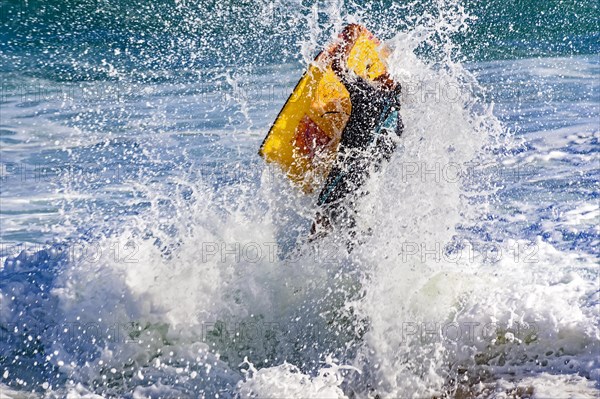 Flight of bodyboarder boy when crashing wave on the beach in Ipanema
