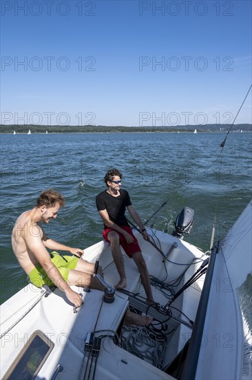 Two young men sailing on a sailboat