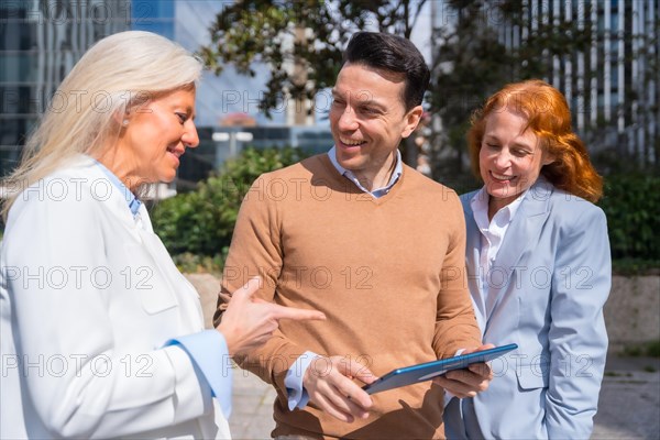 Group executives or businessmen and businesswoman in a business area. Laughing and looking at a tablet