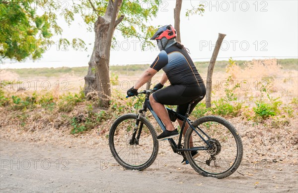 Chubby cyclist on the road. Professional cyclist on a dirt road