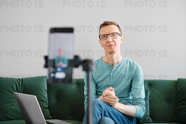 Positive middle aged man using smartphone to record video for vlog channel