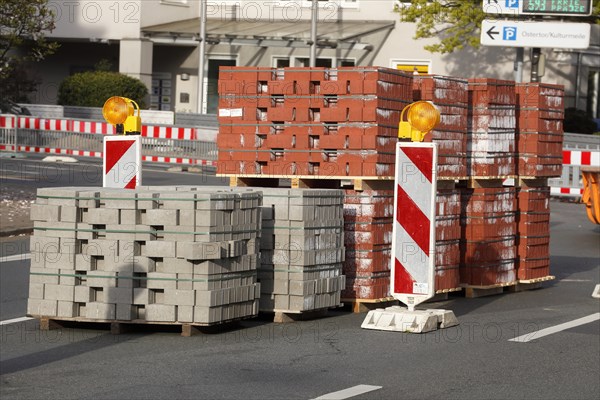 Stacked red building blocks with barrier beacons on a construction site for a cycle path