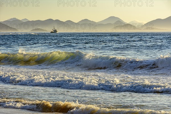 Sunrise on Devil beach in Ipanema in Rio de Janeiro with a fishing boat and mountains in the background.