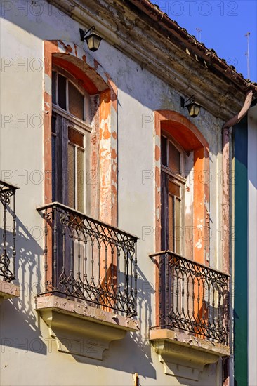 Window of old colonial style house with balcony and colorful frame with peeling paint in the ancient city of Ouro Preto in Minas Gerais