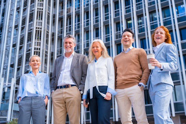 Portrait of cheerful group of coworkers walking outdoors in a corporate office area laughing