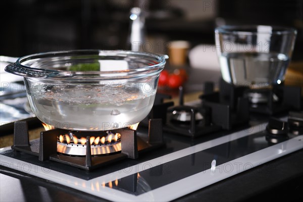 Water boiling in transparent borosilicate glass casserole on gas stove