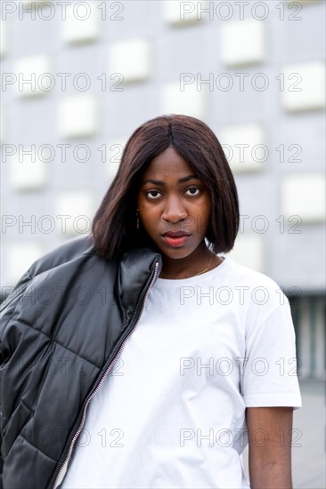 Smiling black woman with sunglasses opening the door of her car. Wearing an orange shirt and enjoying the summer in the city