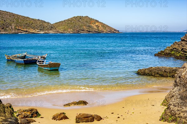 Old wooden fishing boat floating on the colorful and transparent waters of the sea of Buzios in the state of Rio de Janeiro