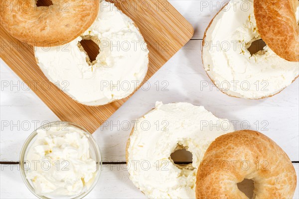 Bagel sandwich for breakfast topped with cream cheese on wooden board from above in Stuttgart