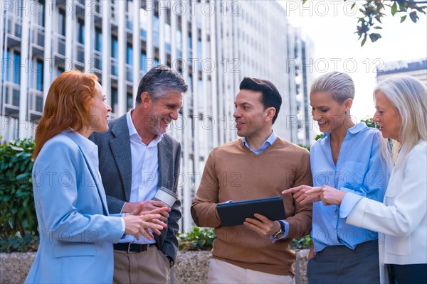 Chatting and seeing work stuff on a tablet. Group executives or businessmen and businesswoman in a business area