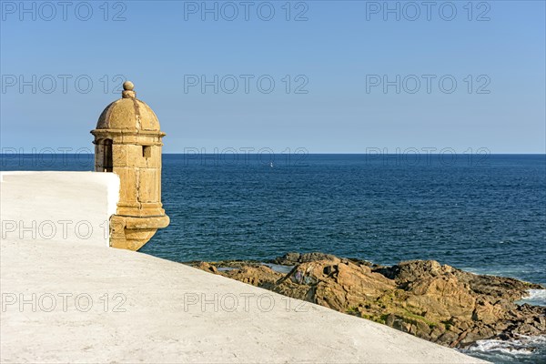 Walls and guardhouse of old fortification with the sea and stones in the background in the city of Salvador in Bahia