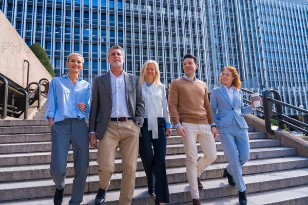 Cheerful group of coworkers outdoors in a corporate office area going down some stairs going to work