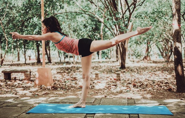 Young woman doing yoga pose warrior III. Spiritual girl practicing yoga Virabhadrasana III outdoors