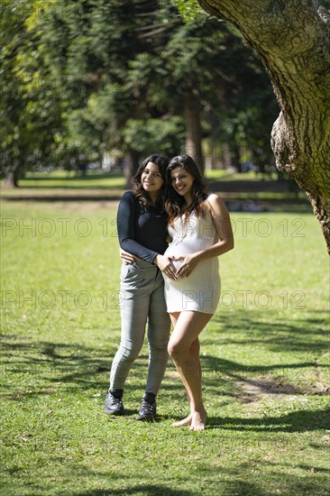 Happy pregnant lesbian couple at outdoors. LGBT