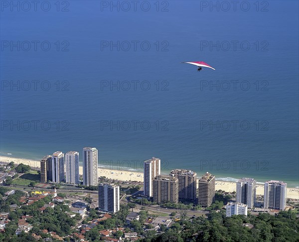 Hang glider flying over the Sao Conrado neighborhood after jumping the ramp located in Pedra Bonita
