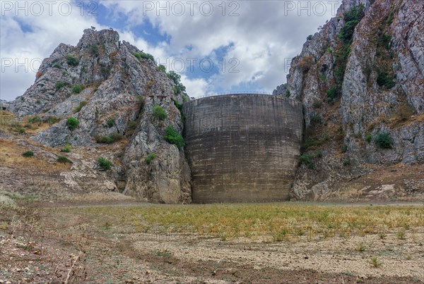 This striking photograph depicts a reservoir dam during a severe drought. The reservoir